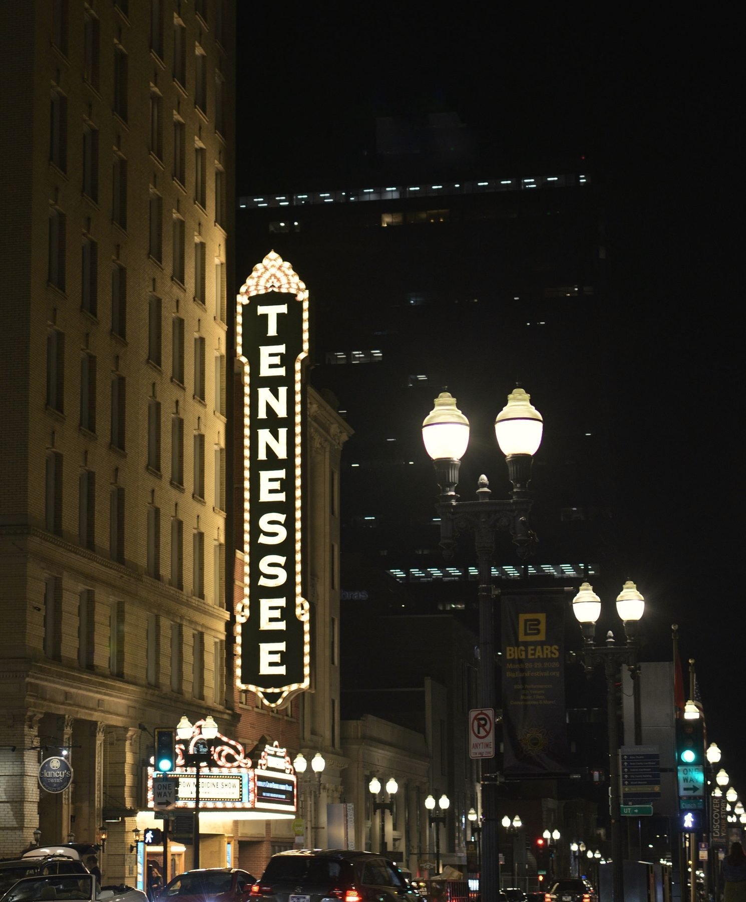A downtown Knoxville street at night with the vertical Tennessee theatre sign lit