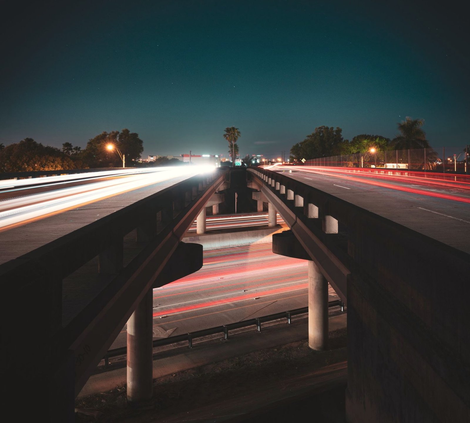 View down the median of a divided highway at dusk with traffic blurred on both sides