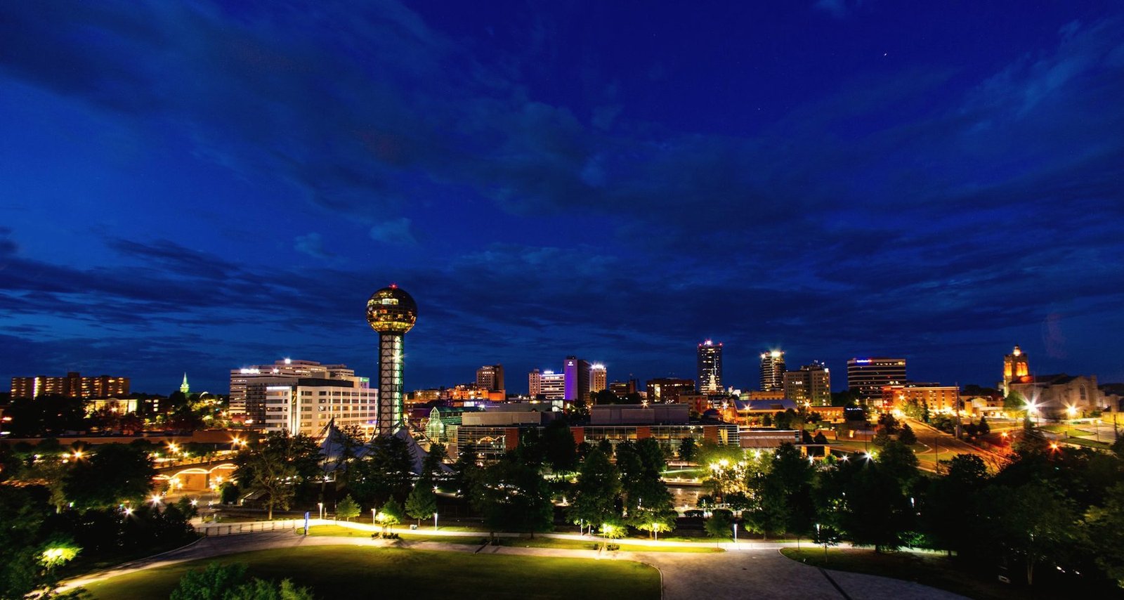 The Knoxville skyline at night under a deep blue sky, the Sunsphere lit at the centre