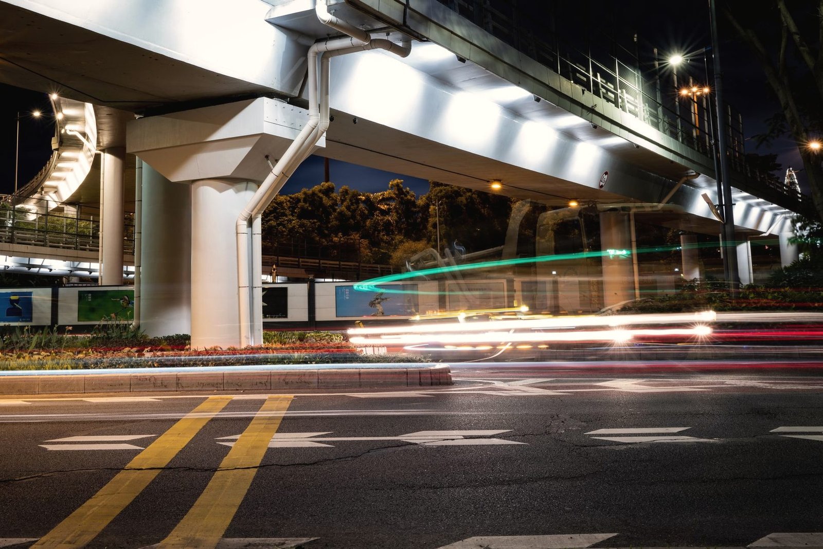 Light trails from passing traffic under a brightly lit elevated highway