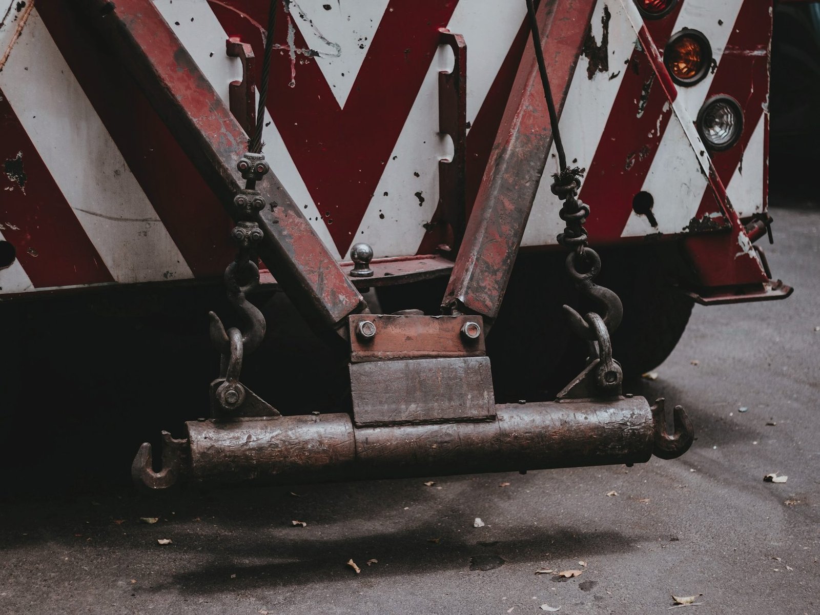 Rear of a wrecker with red and white chevrons, a steel boom and tow hooks